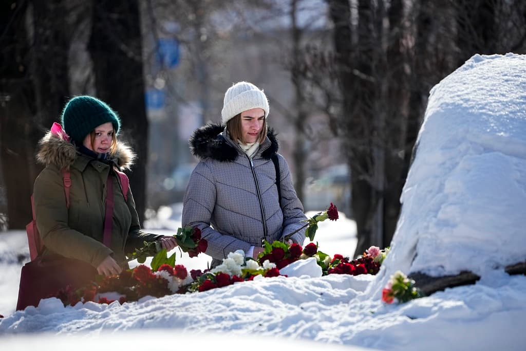 AP/Alexander Zemlianichenko Young women lay flowers to pay the last respect to Alexei Navalny at the monument, a large boulder from the Solovetsky islands, where the first camp of the Gulag political prison system was established at Moscow.